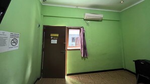 A room with green walls, a brown door, and a window with a curtain.