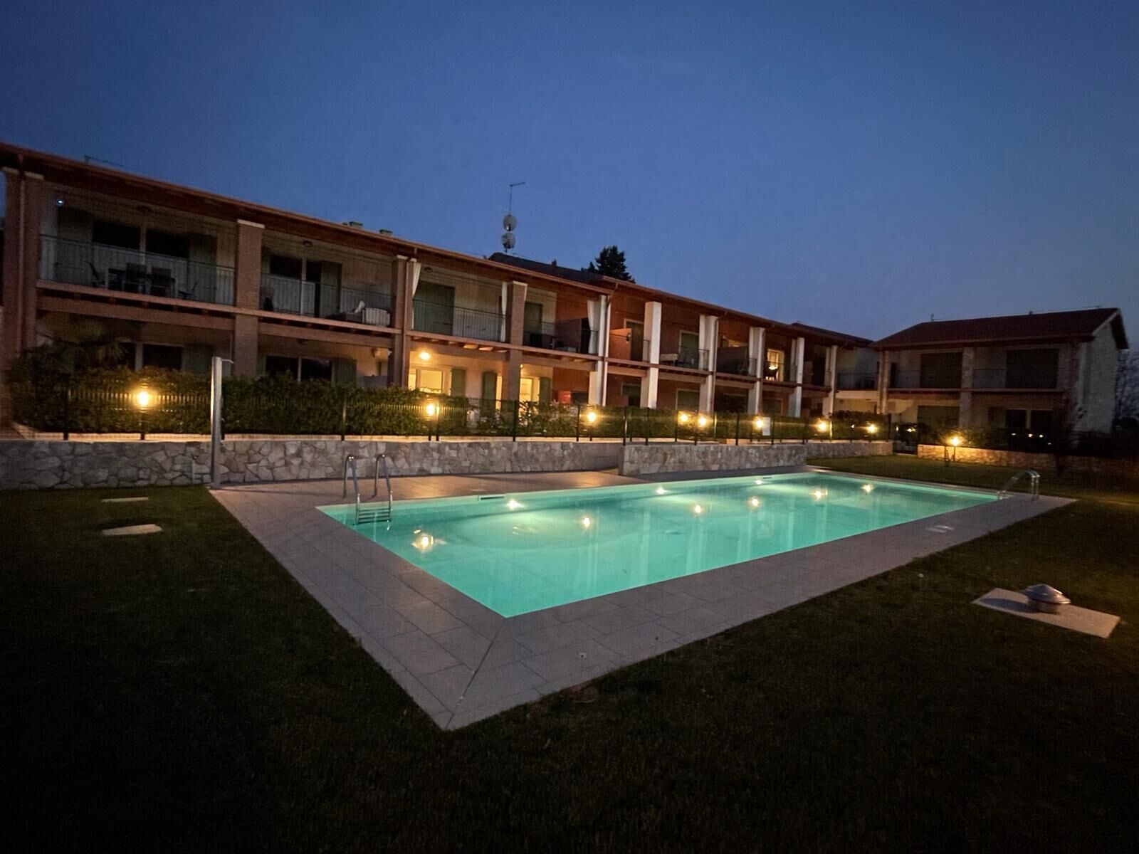 A hotel with a swimming pool, multiple balconies, and a stone facade.