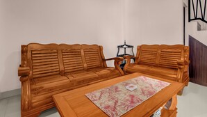 Un ensemble de meubles de salon en bois, comprenant un canapé et une table assortis, un tapis à motifs et un luminaire fixé au mur.