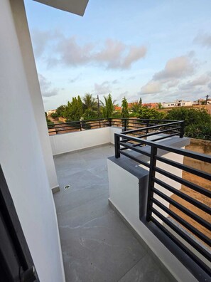 A rooftop terrace with a black railing, a concrete floor, and a view of surrounding buildings and greenery. - Villa with private pool - 3 bedrooms ideal for family weekend getaways (Ngaparou)