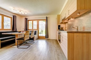 Eine moderne Küche mit Holzausstattung, einem Essbereich mit einer Bank und einem großen Fenster.