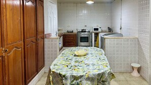 Une cuisine de taille réduite, dotée de meubles en bois, d’un four à micro-ondes, d’un four traditionnel et d’un évier.