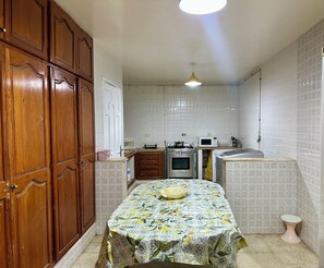 A compact kitchen with wooden cabinets, a microwave, an oven, and a sink. - La Baïa Cosy (La soukra)