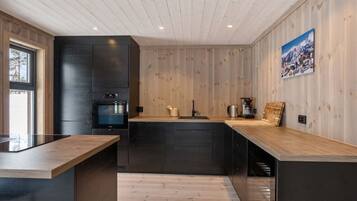 A modern kitchen with wooden paneling, a built-in oven, and a large island with a sink.