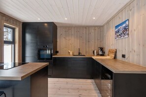 A modern kitchen with wooden paneling, a built-in oven, and a large island with a sink.