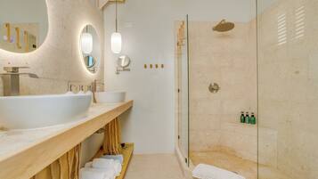 A modern bathroom with a large sink, mirror, and shower.