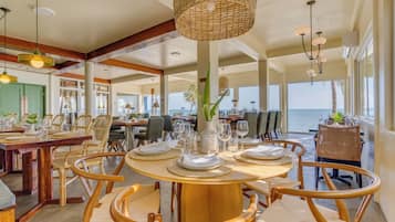 Un comedor espacioso con techos altos, ventanas grandes y vistas al mar.