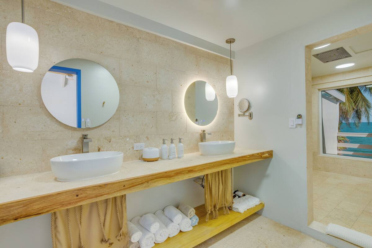 A modern bathroom with two sinks, a large mirror, and a wooden vanity.