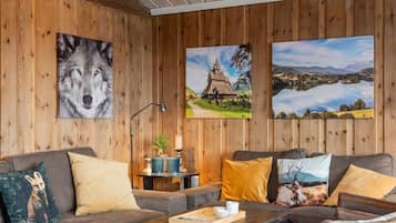 A cozy room with wooden walls, a sofa, a coffee table, and three framed pictures.