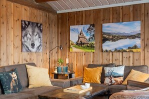 A cozy room with wooden walls, a sofa, a coffee table, and three framed pictures.