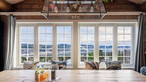 A dining area with a large table, multiple windows, and a view of a landscape. - Trysil Ski-in/out | 6 BR | Sauna (Trysil)