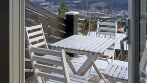 A balcony with white chairs and a table, overlooking a cityscape with distant mountains. - Trysil Ski-in/out | 6 BR | Sauna (Trysil)