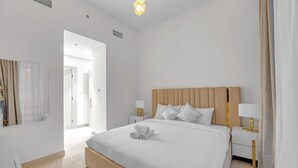 A hotel room with a large bed, bedside tables, a mirror, and a view of the hallway. - 3 Bedroom in Forte Tower Near Burj Khalifa (Dubai)