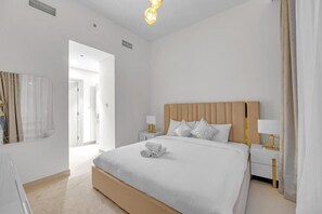 A hotel room with a large bed, bedside tables, a mirror, and a view of the hallway. - 3 Bedroom in Forte Tower Near Burj Khalifa (Dubai)