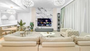 A modern living room with a large flat-screen TV, a dining area with a table and chairs, and a seating area with sofas and a coffee table. - 3 Bedroom in Forte Tower Near Burj Khalifa (Dubai)