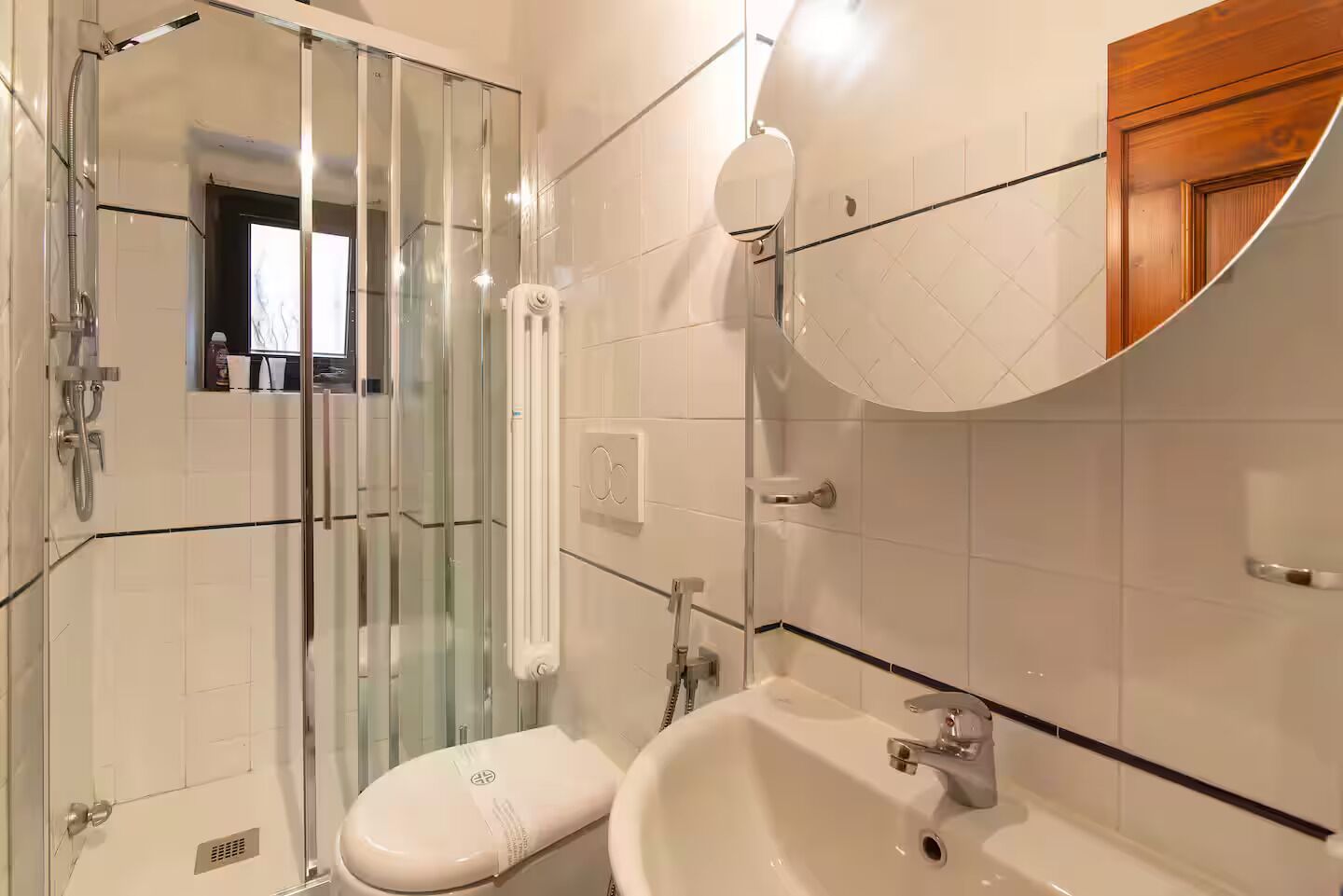 A bathroom with a glass shower enclosure, a toilet, and a sink.