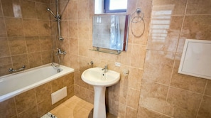 A bathroom with a bathtub, a sink, and a mirror. - Penthouse Duplex Large 2 Bedroom MP1 (Bansko)