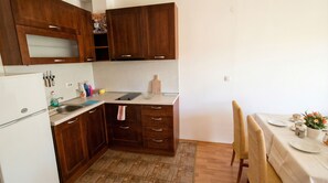 Cozinha compacta com armários de madeira, pia e área de jantar com mesa posta para dois.