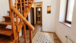 Eine Holztreppe führt zu einem Badezimmer mit Waschbecken und Fenster.