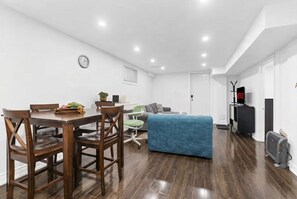 Una sala de estar moderna con una mesa de comedor, sillas, un sofá azul, un televisor de pantalla plana y un calentador.