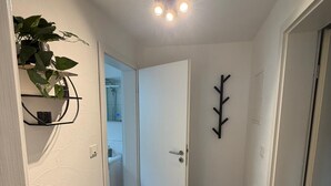 A hallway with a white door, a black wall-mounted coat rack, and a potted plant. - My Altstadt Domizil - Domizil "Freiraum" (Hallenberg)
