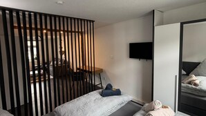 A modern hotel room with a bed, a desk, a chair, a TV, and a mirror. - My Altstadt Domizil - Domizil "Freiraum" (Hallenberg)