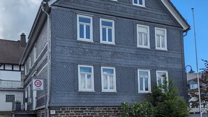 A multi-story building with a dark grey facade, white window frames, and a stone base. - My Altstadt Domizil - Domizil "Freiraum" (Hallenberg)