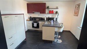 A modern kitchen with white cabinets, a central island, and a ceiling light fixture. - My Altstadt Domizil - Domizil "Freiraum" (Hallenberg)