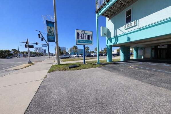 A street view with a 'Beachview Condominium' sign, a traffic light, and a turquoise building with a balcony. - Beachview 324 - Studio Condo - Walk To Shrimp Fest and Hangout (Gulf Shores)