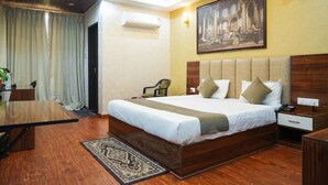 Een hotelkamer met een groot bed, een bureau, een stoel en een schilderij aan de muur.