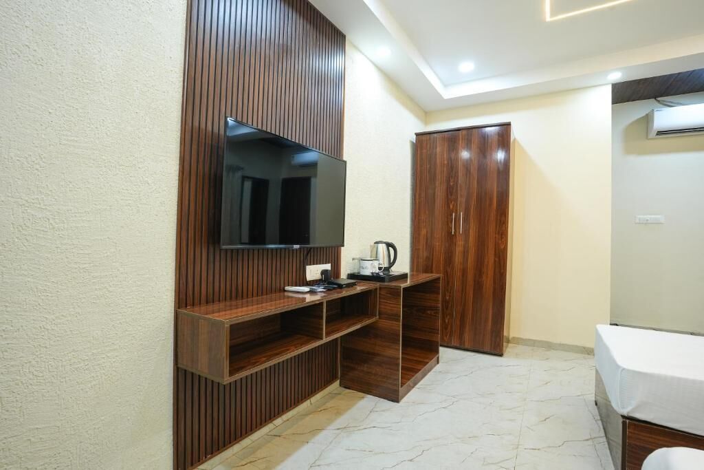 A modern bathroom with a wooden vanity, a mirror, a television mounted on the wall, and a wardrobe.