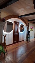 Un pasillo con un arco de ladrillo, una puerta de madera y una escultura de jirafa.