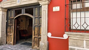 Une entrée d’immeuble avec un arc en pierre, une plaque de numéro et une fenêtre grillagée.