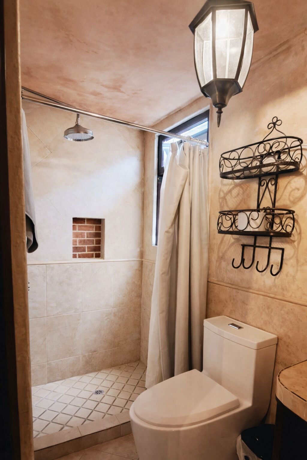 A compact bathroom with a shower, toilet, and a wall-mounted light fixture.