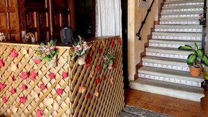 A wooden reception desk with a lattice design, a staircase with patterned tiles, and a potted plant.