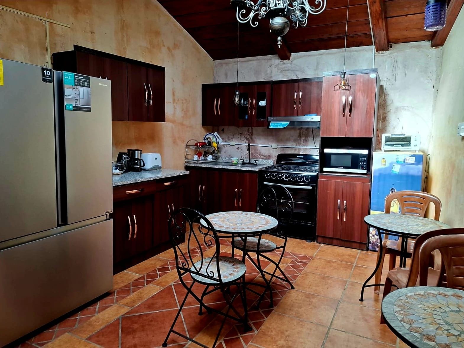 A compact kitchen with a refrigerator, stove, microwave, and dining area with two chairs and a small table.