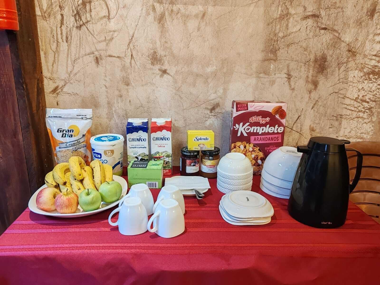 A breakfast table with various food items and a coffee pot.