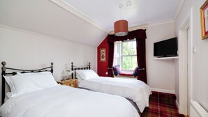 A bedroom with two beds, a television on a shelf, and a window with curtains. - Country House Near Loch Earn (Lochearnhead)