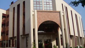 Un edificio moderno con un arco central, ventanas amplias y columnas.