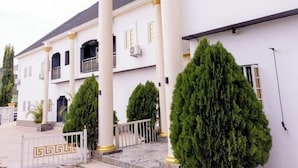 A white building with columns and a covered entrance. - Triple J's Apartment  (Benin City)