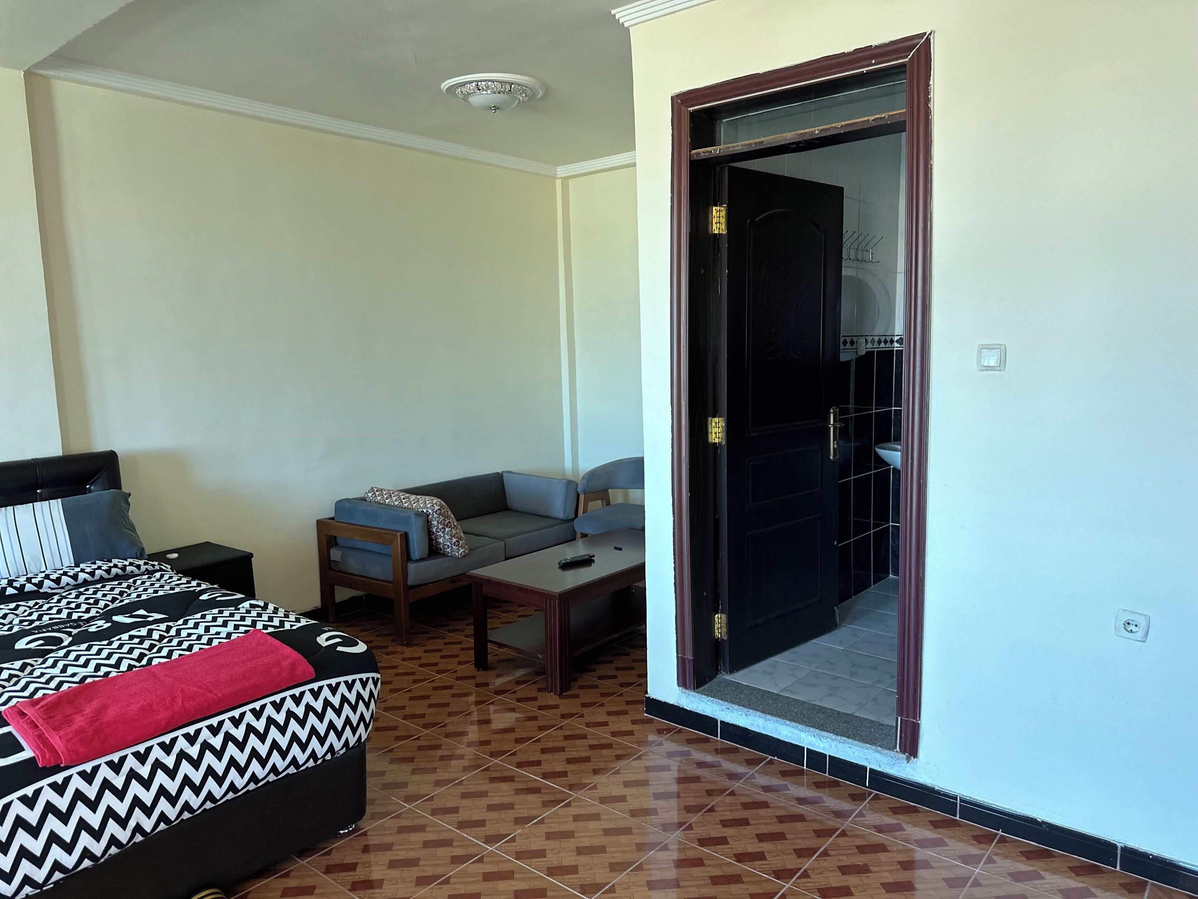 Un dormitorio con cama, sofá, una mesita y espejo.