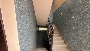A staircase with a handrail, leading to a landing with a window. - Safe Land Guest House  (Mek'ele)