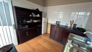 A kitchen with dark wooden cabinets, a refrigerator, a sink, and a stove. - Safe Land Guest House  (Mek'ele)