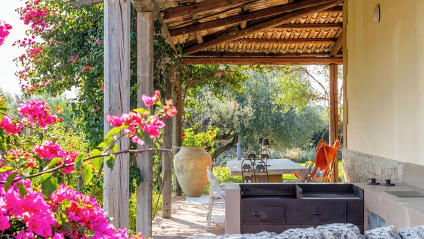 An outdoor patio with a wooden pergola, a stone bench, and a large vase. - Villa Torre Pizzuta (Noto)