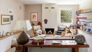 A cozy living room with a fireplace, comfortable seating, and a bookshelf. - Villa Torre Pizzuta (Noto)