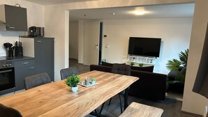 A modern kitchen with a dining area, a flat-screen TV, and a small plant on the table. - ME LIVING - Holiday apartment - 2 bathrooms (Lemgo)