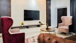 Un salon moderne avec un téléviseur à écran plat, un banc et deux fauteuils.