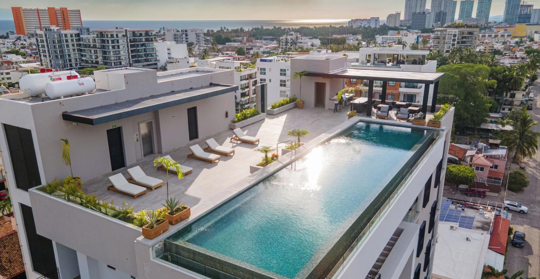 A rooftop pool with lounge chairs and a view of the cityscape.
