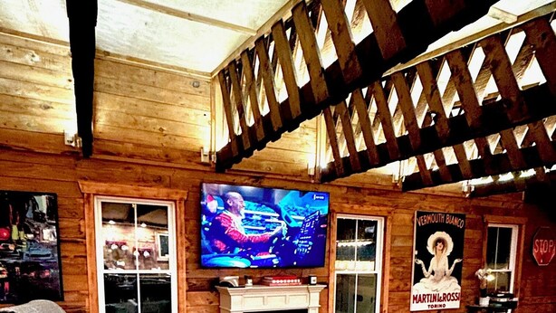 A cozy living room with a fireplace, leather sofas, and a television mounted on the wall. - Stay in this historic Automotive-themed huge Apt. Located in charming Whitingham (Whitingham)