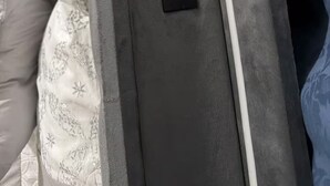 En seng med gråt sengegavl, et strømstik og en USB-port.